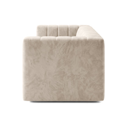 Side profile view of a beige tufted sofa on white background