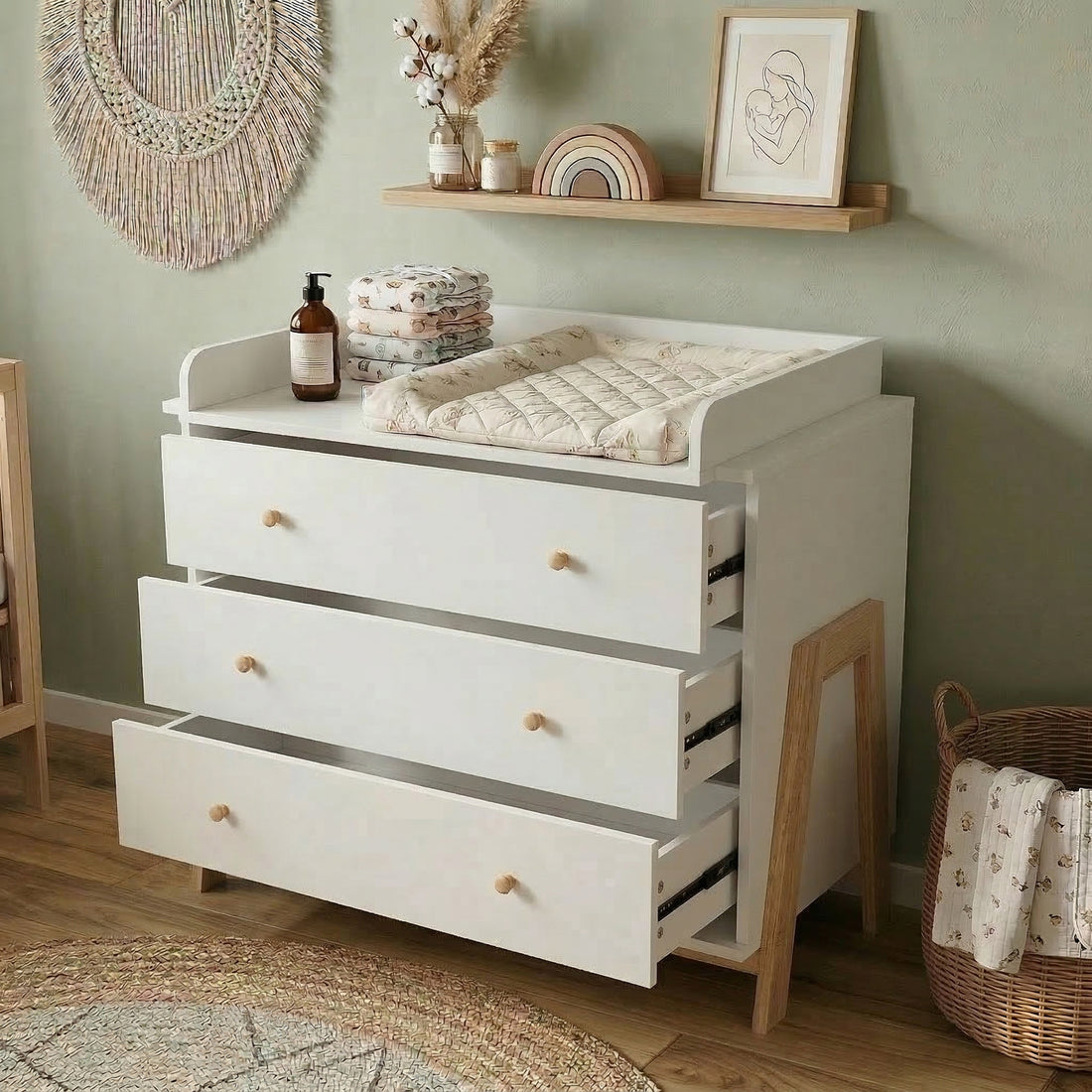 White changing table dresser in a nursery with shelf décor and woven wall hanging