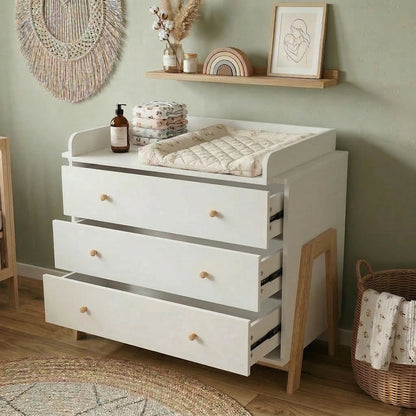 White changing table dresser in a nursery with shelf décor and woven wall hanging