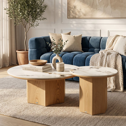 Two round marble-top tables styled in a living room beside a blue velvet sofa.
