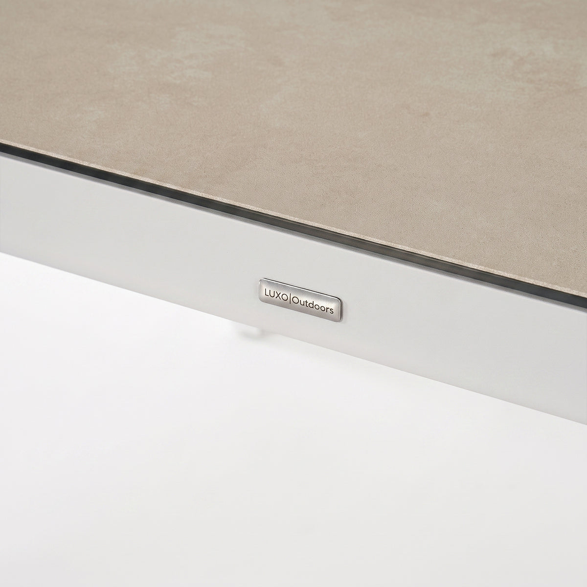 Close-up of the edge of a rectangular tabletop with a brand tag on a white background.