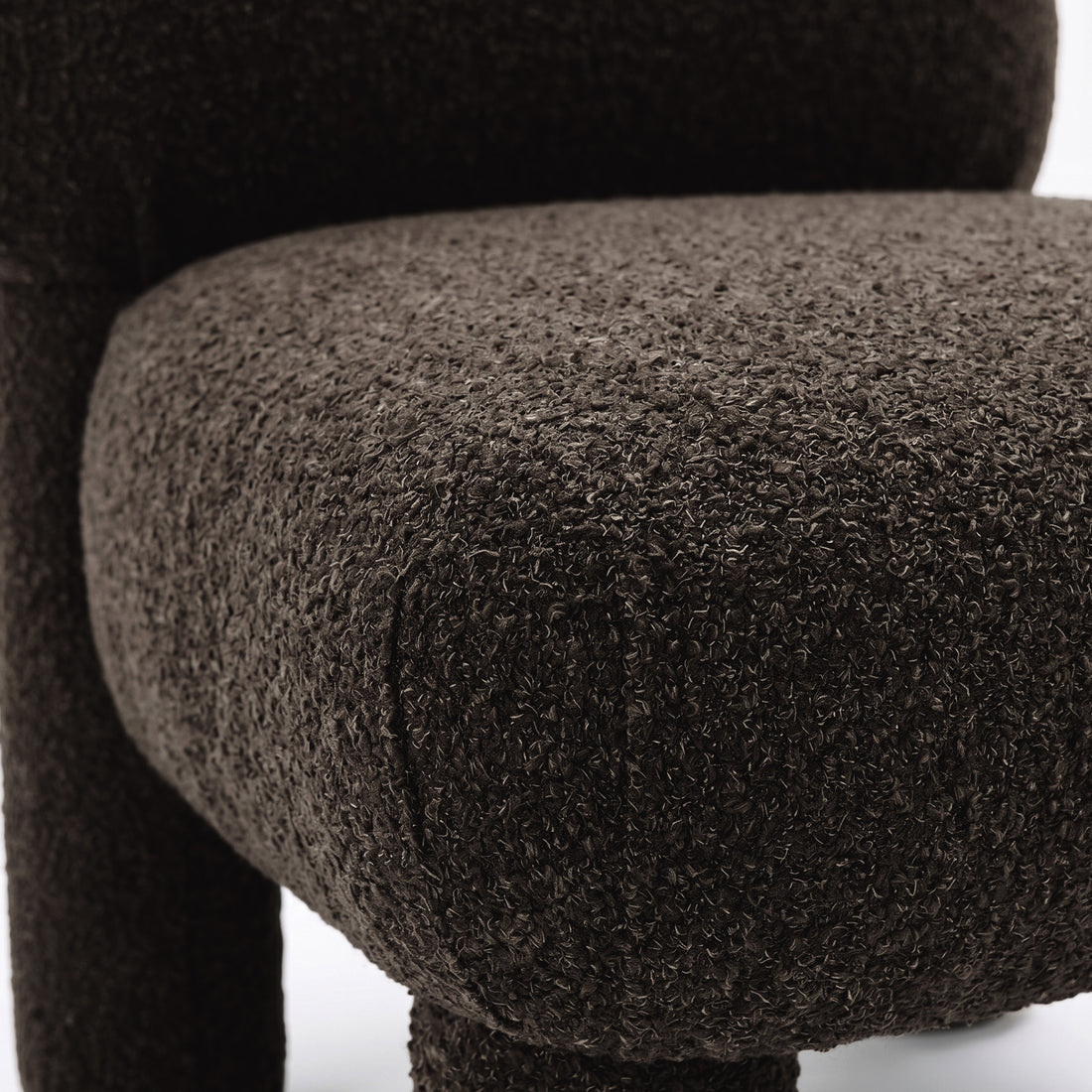 Close-up of dark brown boucle fabric and cushion edge of chair
