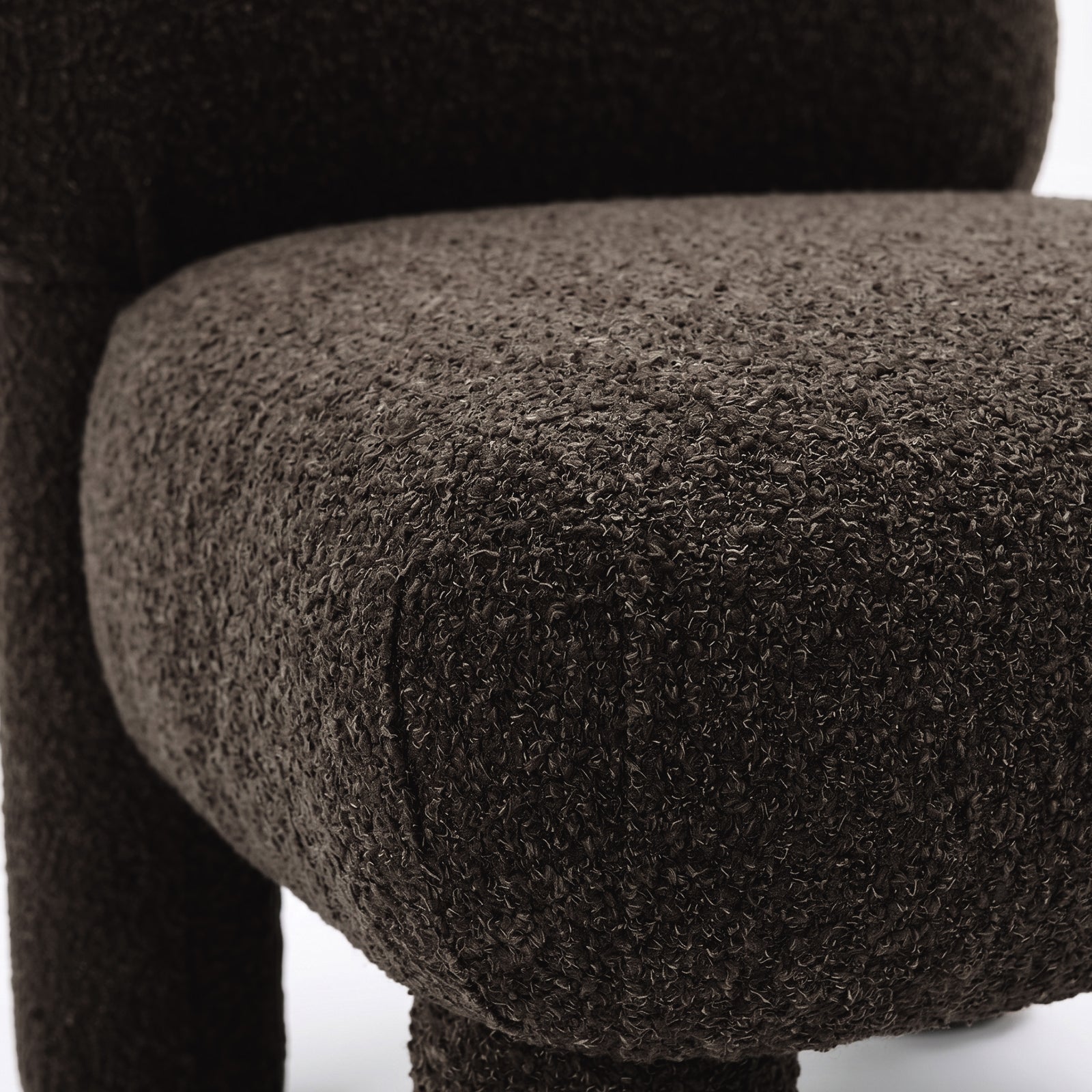 Close-up of dark brown boucle fabric and cushion edge of chair