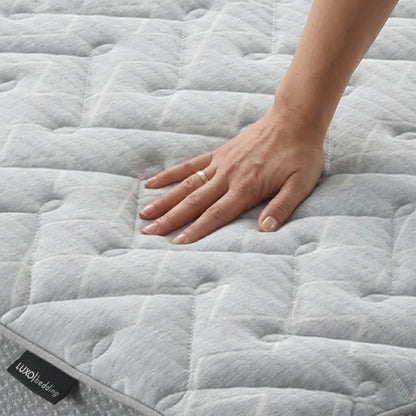 Hand pressing on quilted mattress surface with brand tag visible