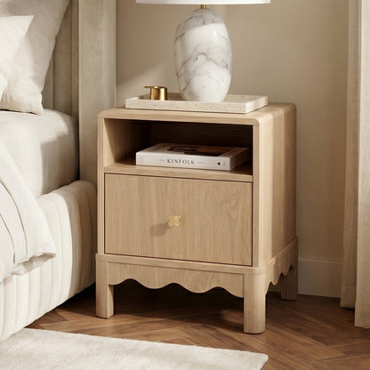 Light wood nightstand styled beside a bed in a cozy bedroom