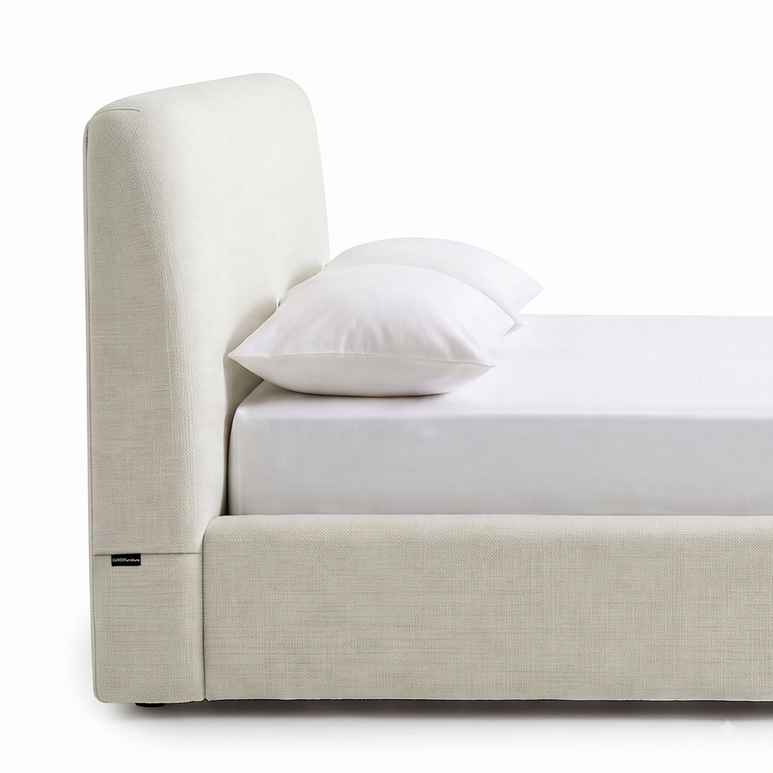 Side view of an upholstered bed with mattress and pillows on a white background