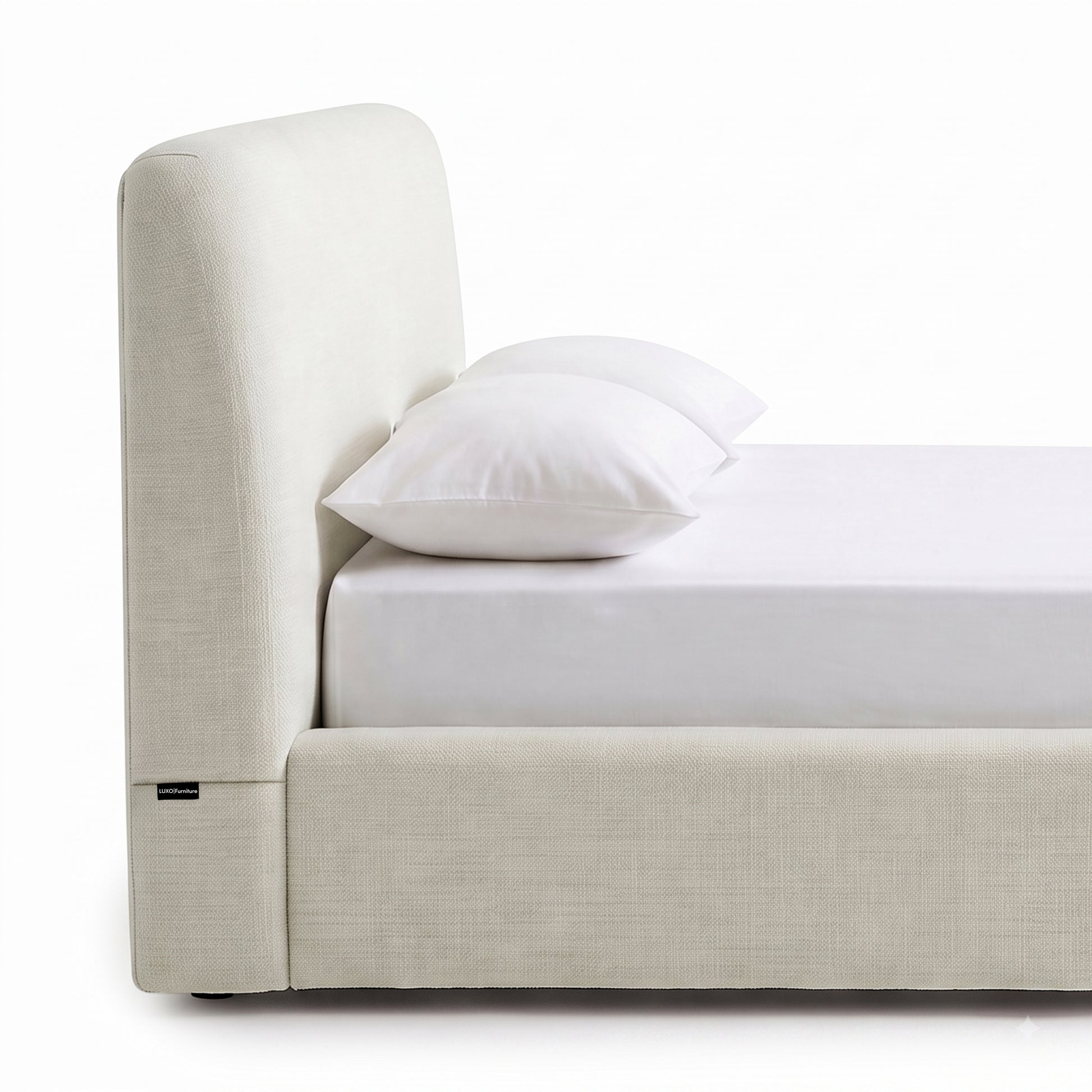 Side view of an upholstered bed with mattress and pillows on a white background