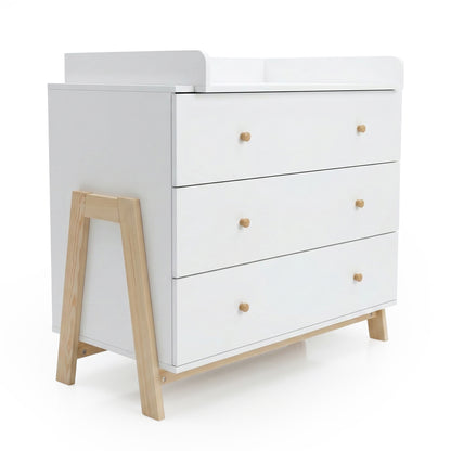 White dresser/changing table with light wood legs and knobs on a white backdrop