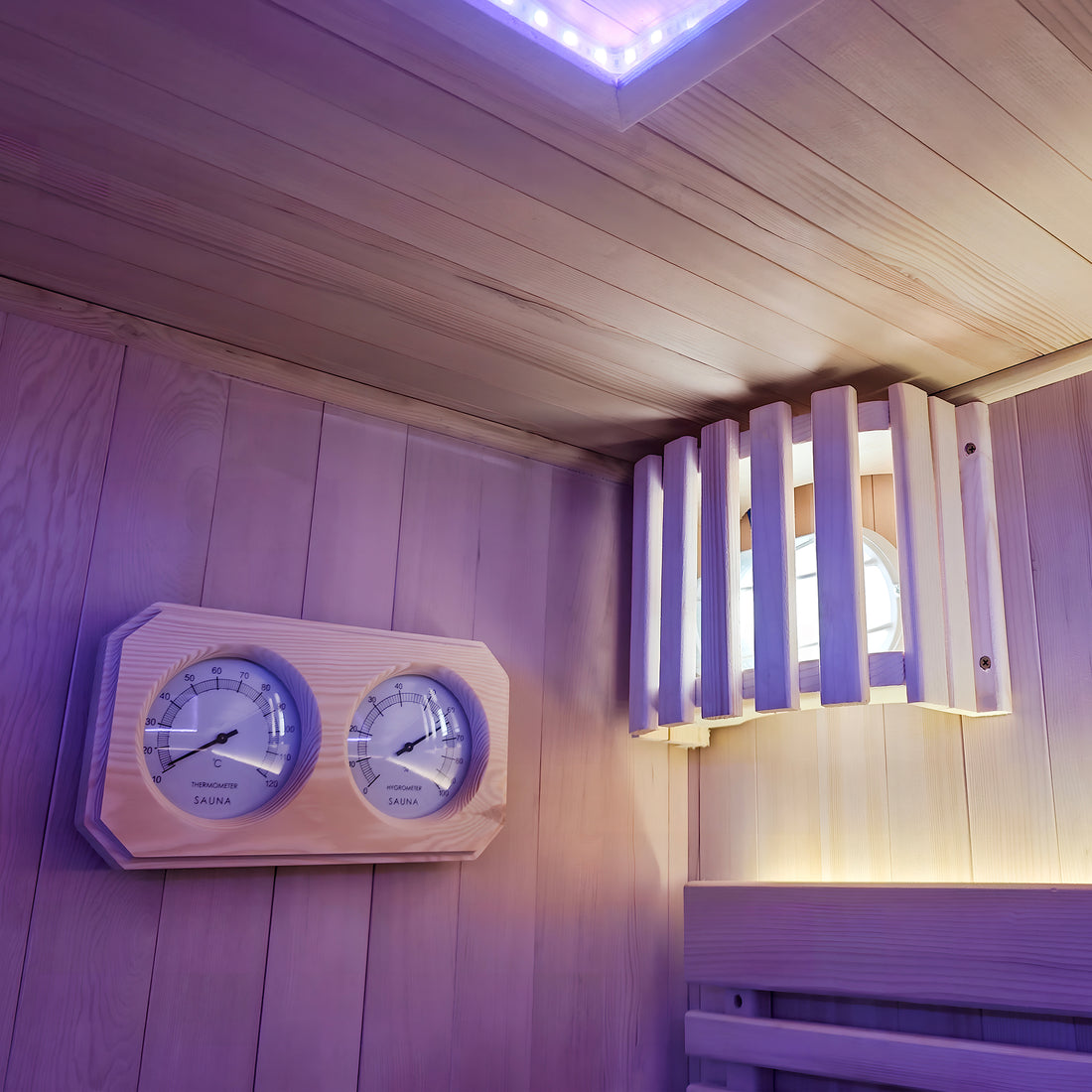 Wooden sauna wall with temperature and humidity dials and a covered light fixture