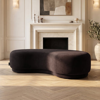 Chocolate brown curved bench seat in an elegant living room with fireplace and decor