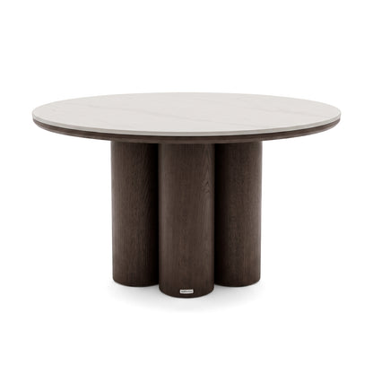 Modern round dining table with light tabletop and three dark cylindrical legs on a white background