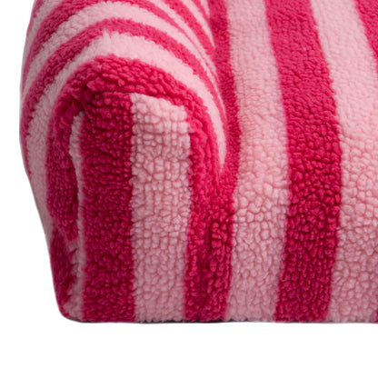 Close-up view of the corner of a pink and light pink striped plush surface on white background