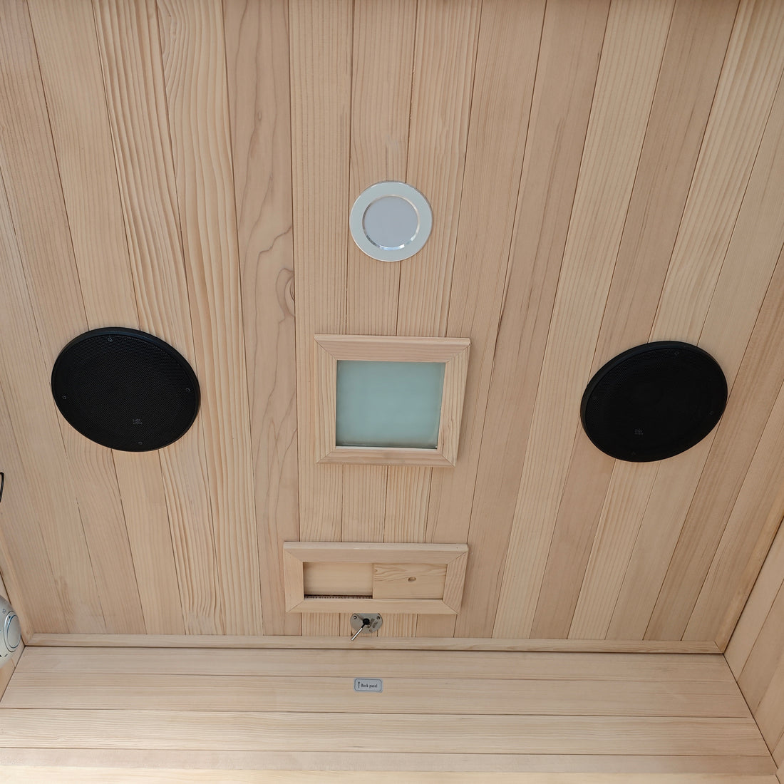 Wooden sauna ceiling with vents, lights, and speaker-like features.
