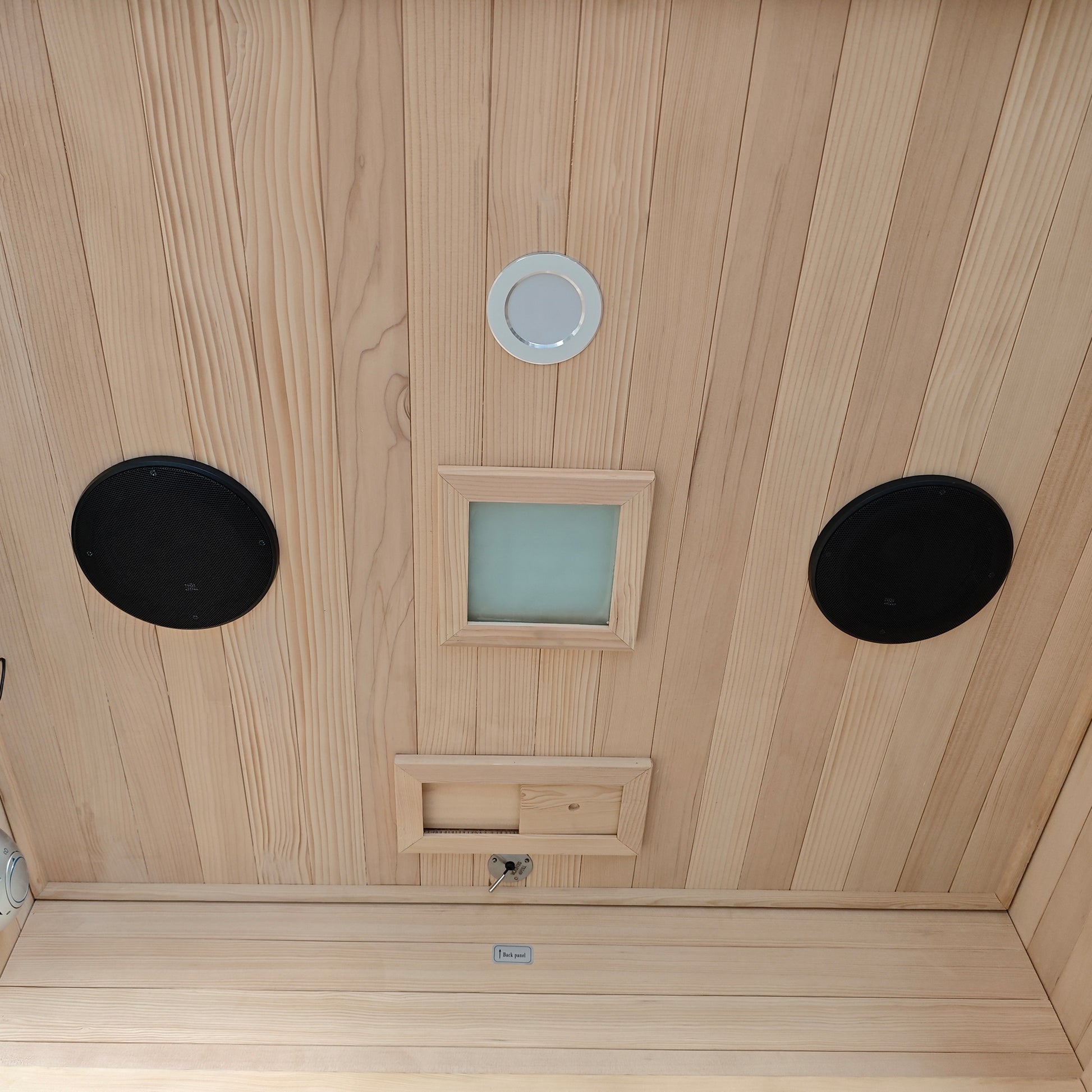 Wooden sauna ceiling with vents, lights, and speaker-like features.