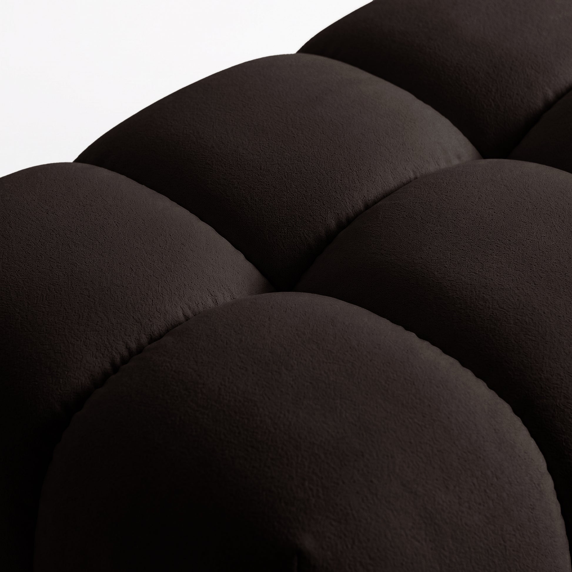 Close-up of chocolate brown upholstered fabric and stitching on a white background.