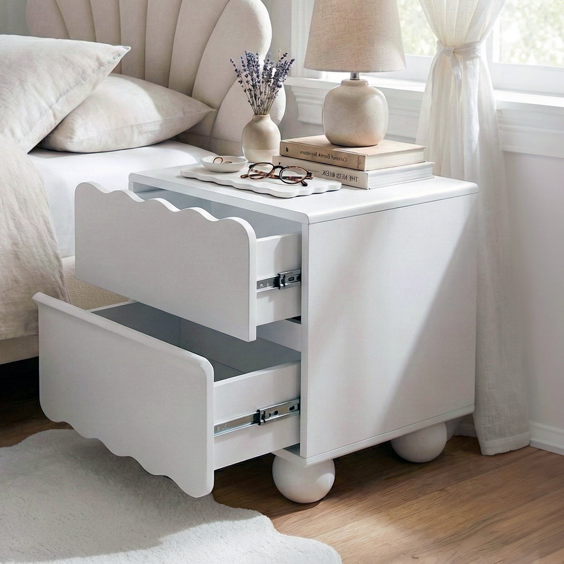 White nightstand with open drawers beside a bed with decor
