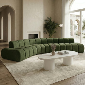 Curved green sectional sofa in a styled living room with coffee table and décor