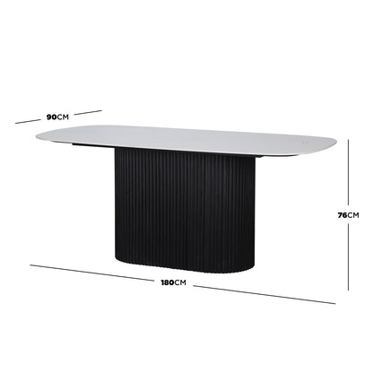 Aeris 180cm Marble Look Dining Table With Wood Base in Black features a white elongated oval tabletop and a central pedestal with vertical ribbing, offering a modern, elegant dining solution.