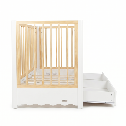 White and natural wood baby crib with pull-out storage feature on white background