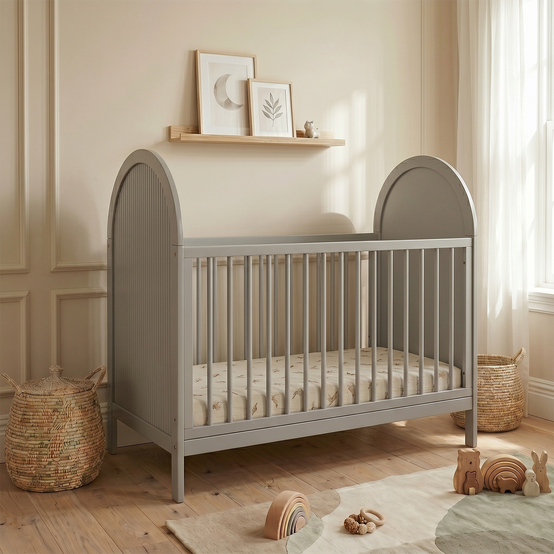Grey crib in a styled nursery room with decorative baskets and toys