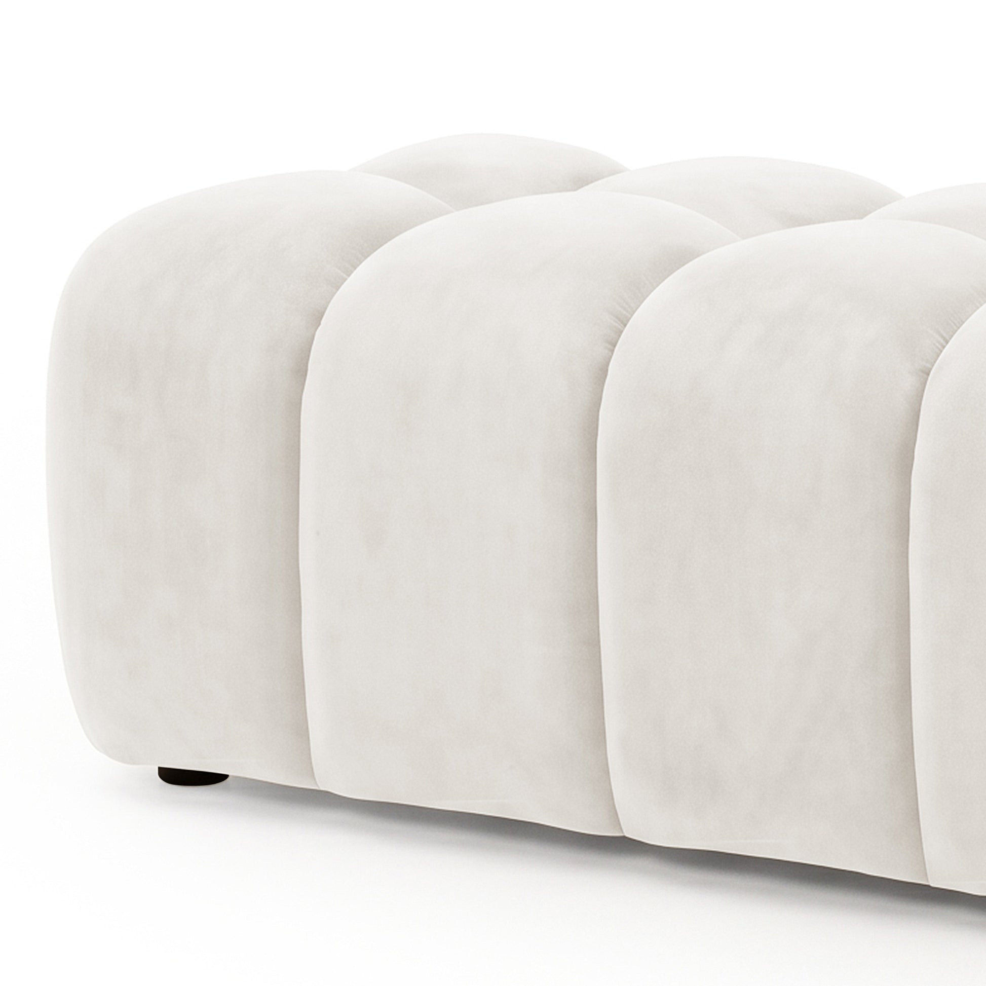 Light beige tufted upholstered ottoman bench partially cropped on a white background