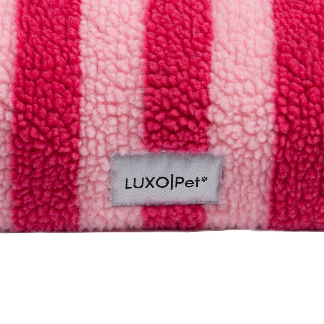 Close-up of pink and light pink striped plush fabric with 'LUXO|Pet' brand tag on a white background