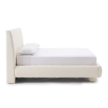 Side view of an upholstered bed on a white background