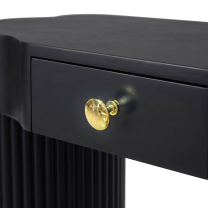 Close-up of black furniture drawer with gold knob and fluted side detail on a white background