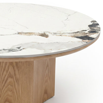Partial view of a round table with a marble top and wood base on a white background.