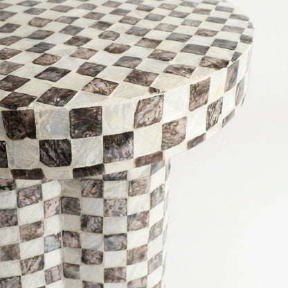 Close-up of the top section of a checkerboard-patterned pedestal on white background
