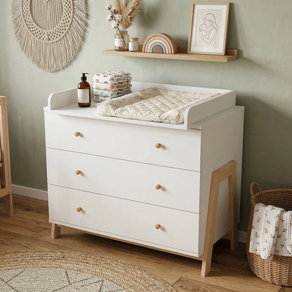 White dresser with wooden knobs in a cozy nursery with basket and rug