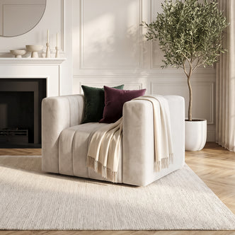 Beige armchair styled in a living room with decorative pillows and a throw