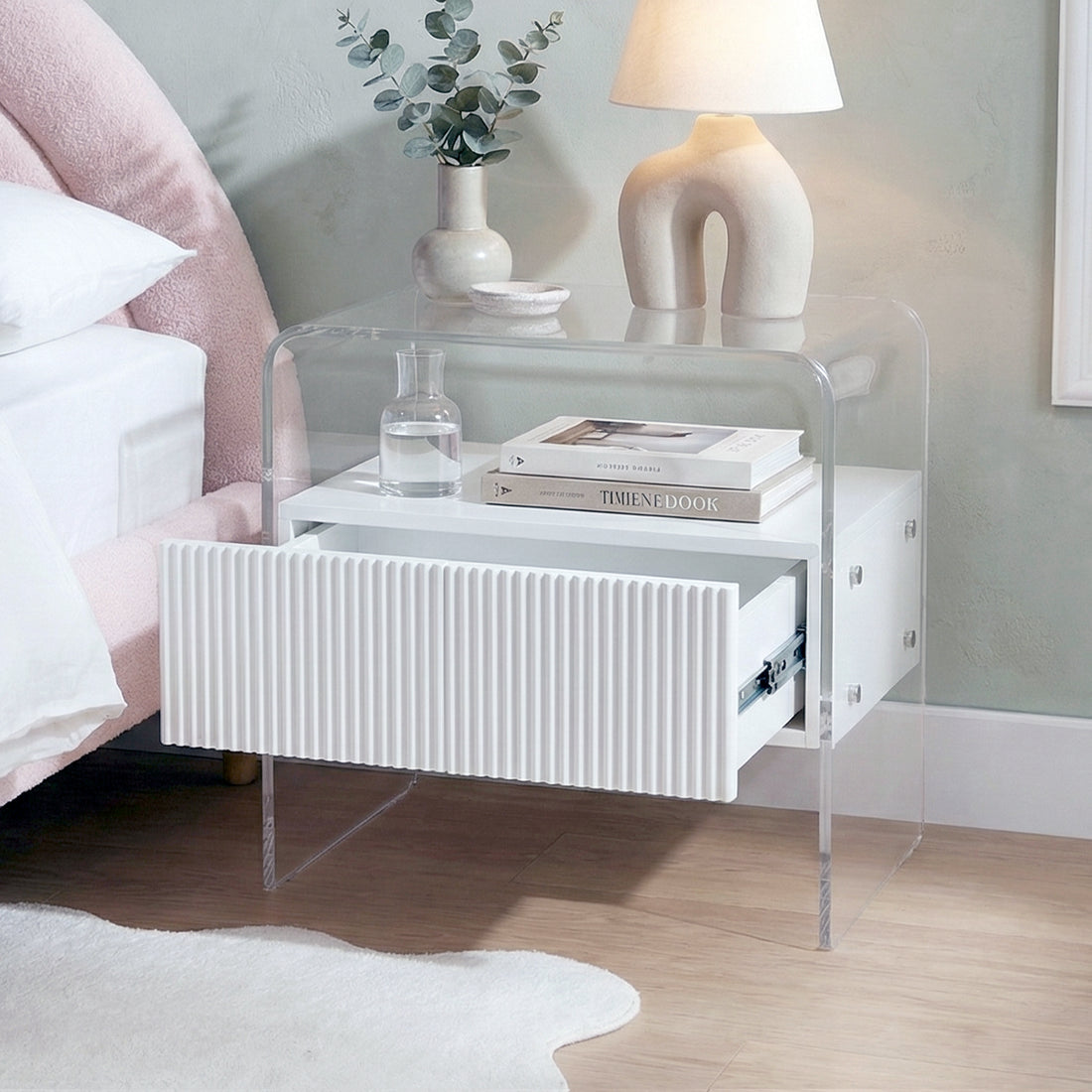 white acrylic nightstand next to bed with open drawer in styled room