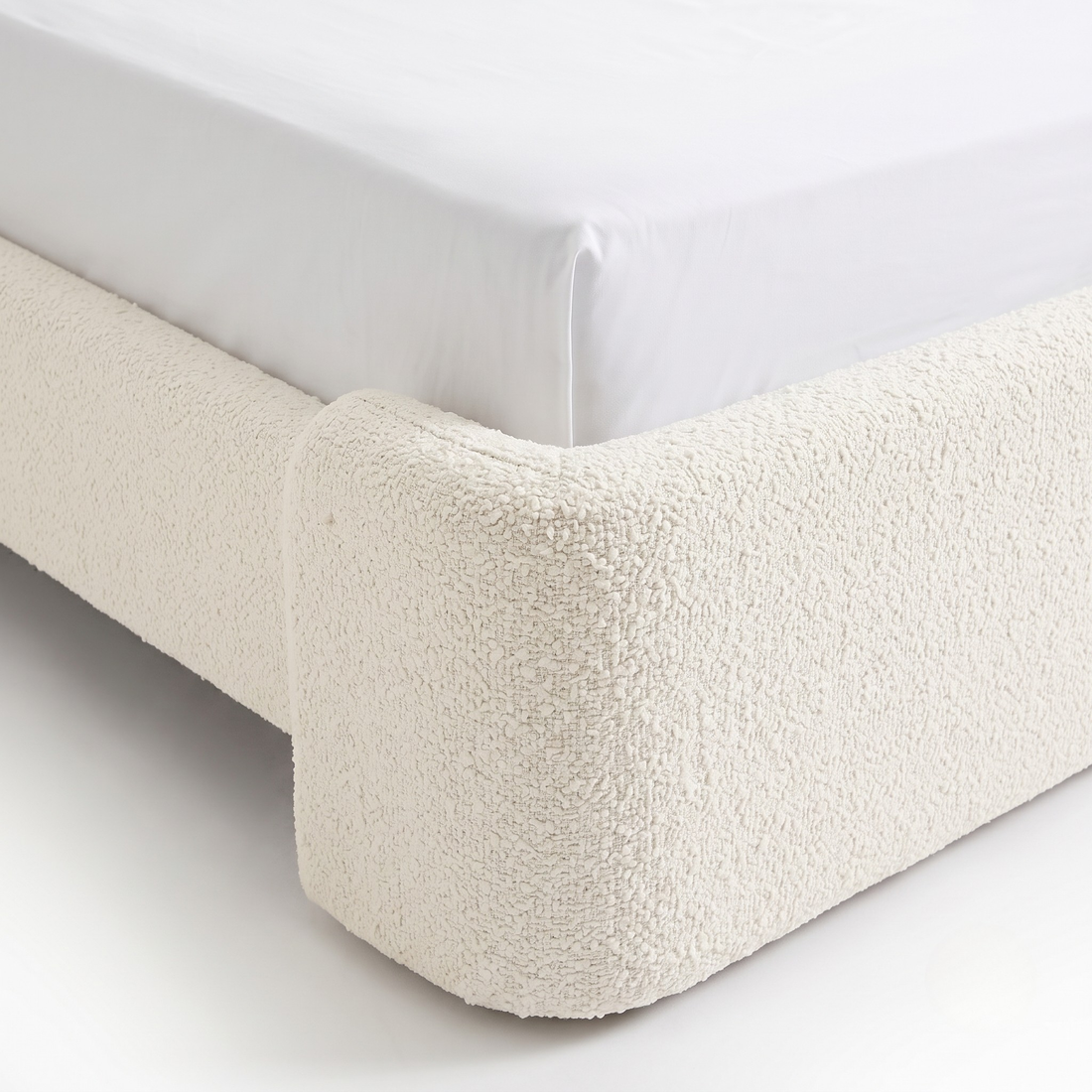 Close-up of upholstered bed corner on white background