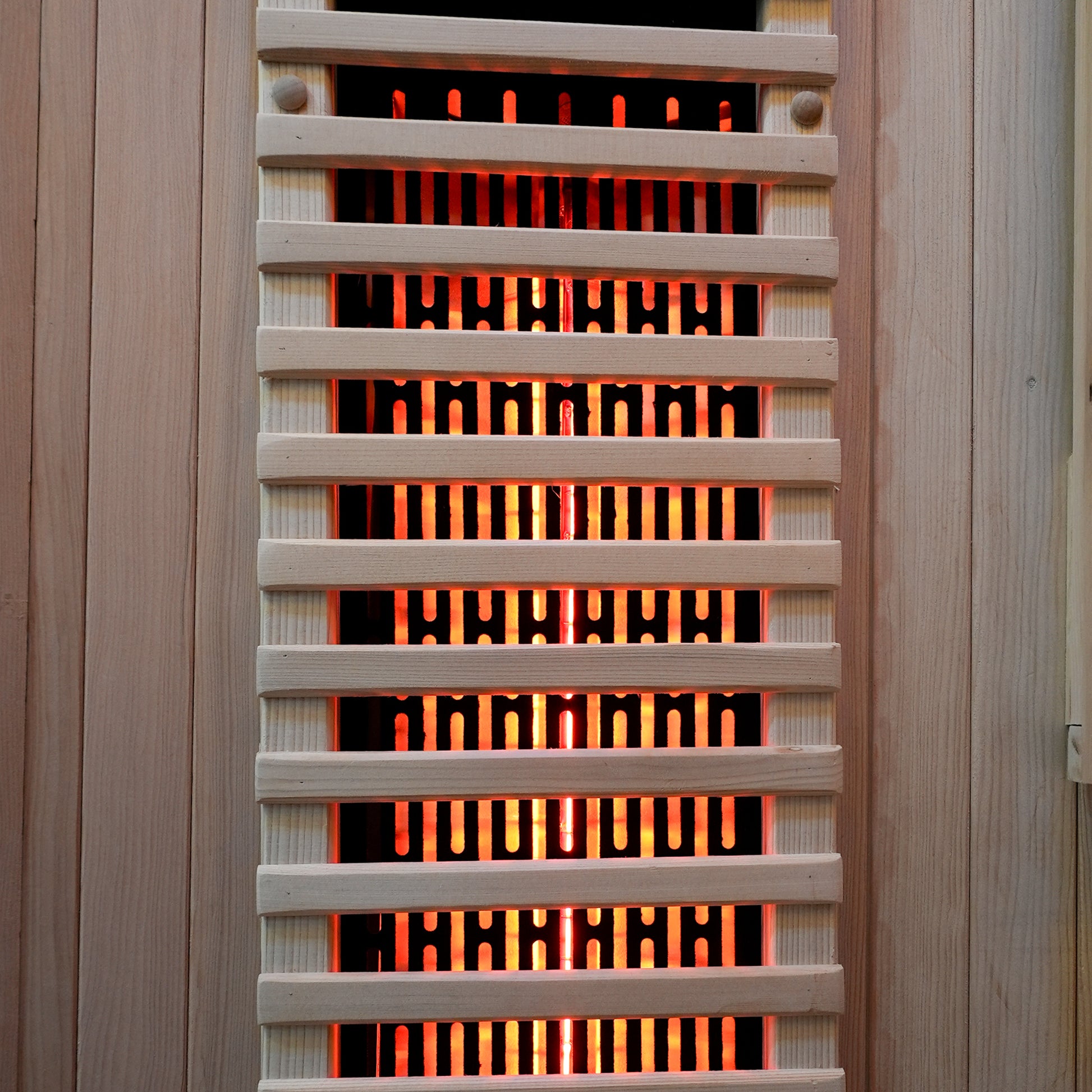Close-up of a sauna heater with glowing heating elements behind a grill