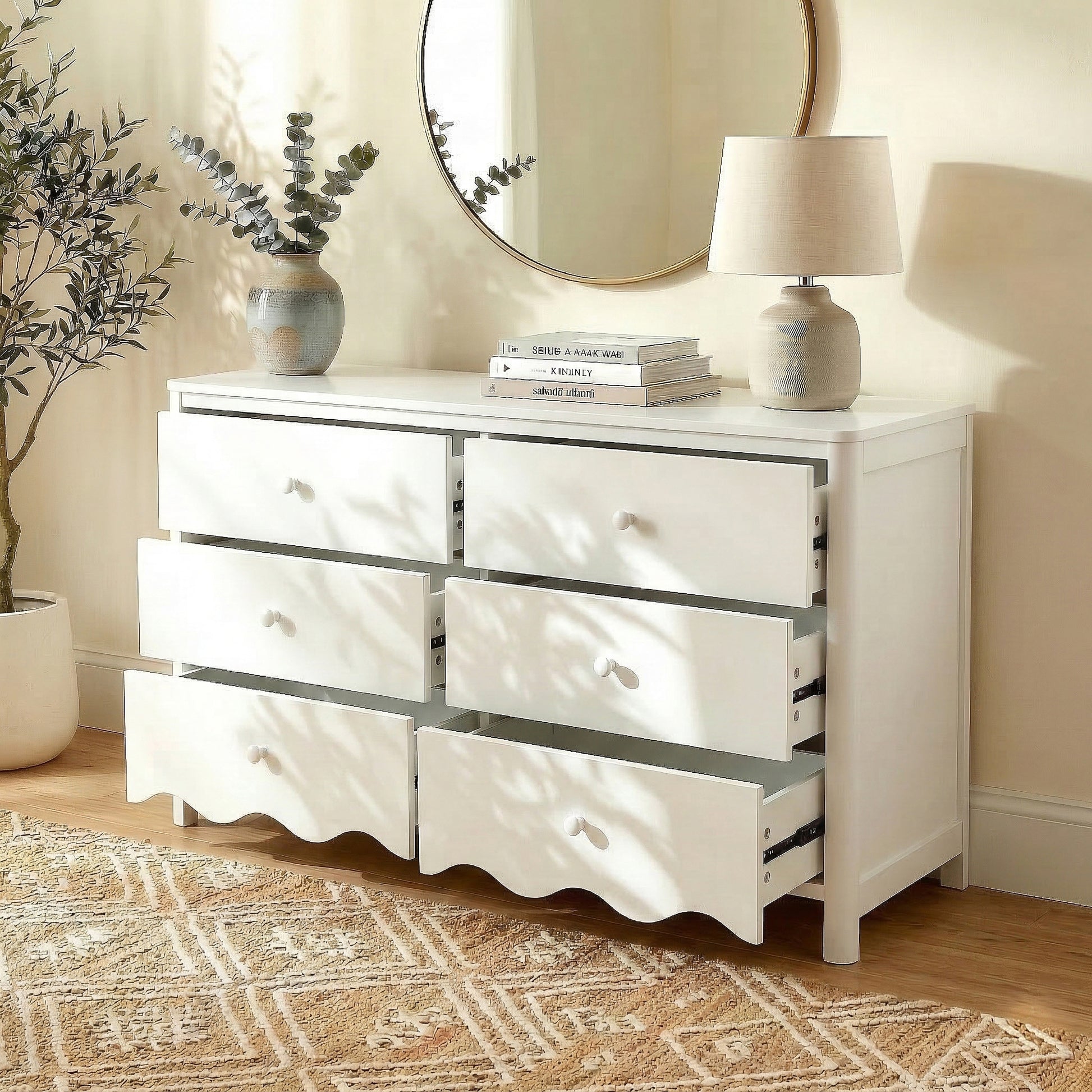 White dresser in inviting room setting with plant, books, lamp, and round mirror