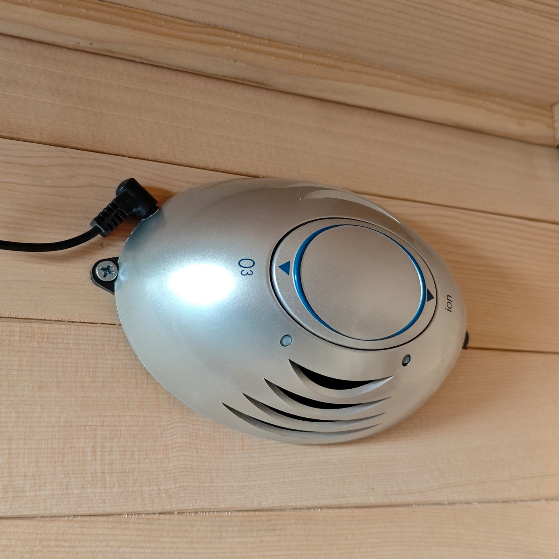 Small oval electronic device mounted on a wooden wall or ceiling.