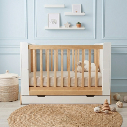 Baby crib in a nursery with blue paneled walls and decor