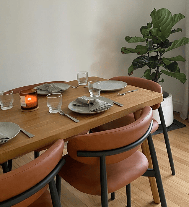 Timber dining table with tan chairs and place settings indoors